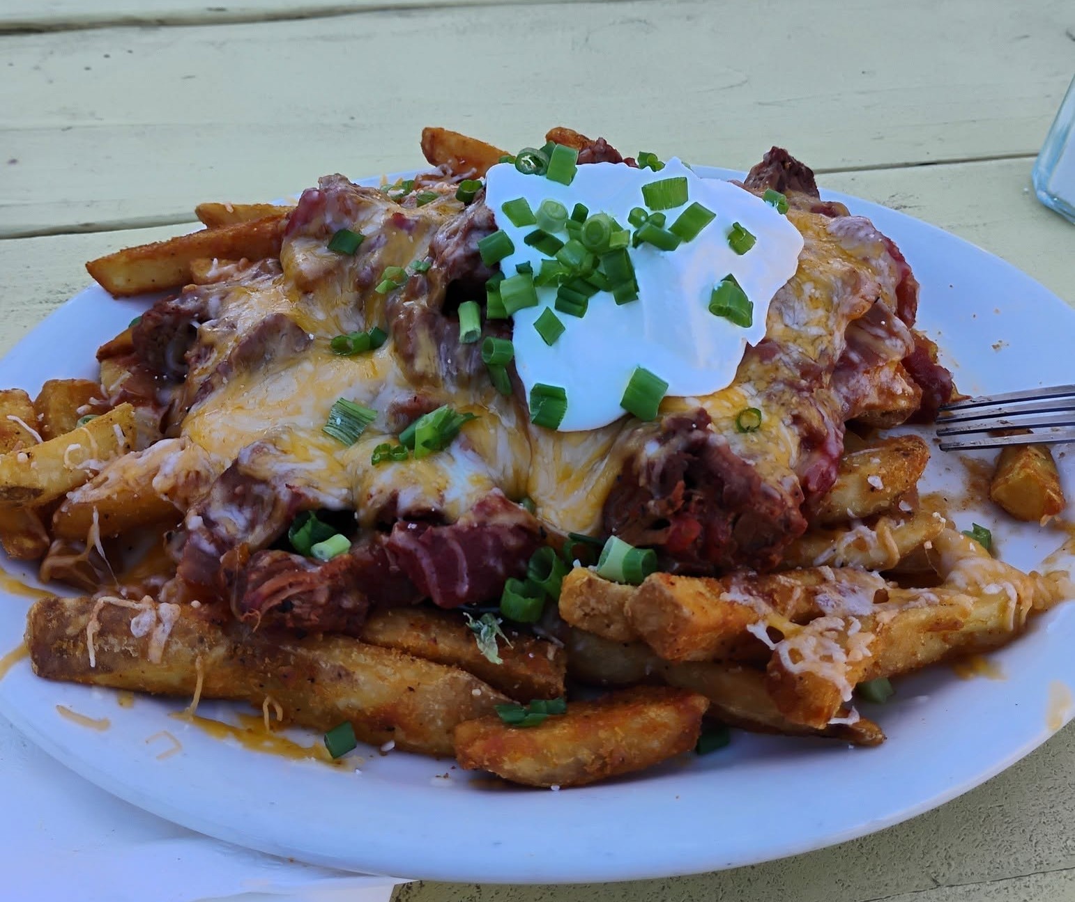 Chili Cheese Fries at Pappy & Harriet’s — A plate of loaded steak fries topped with melted cheese, smoky tri‑tip chili, sour cream, and green onions.