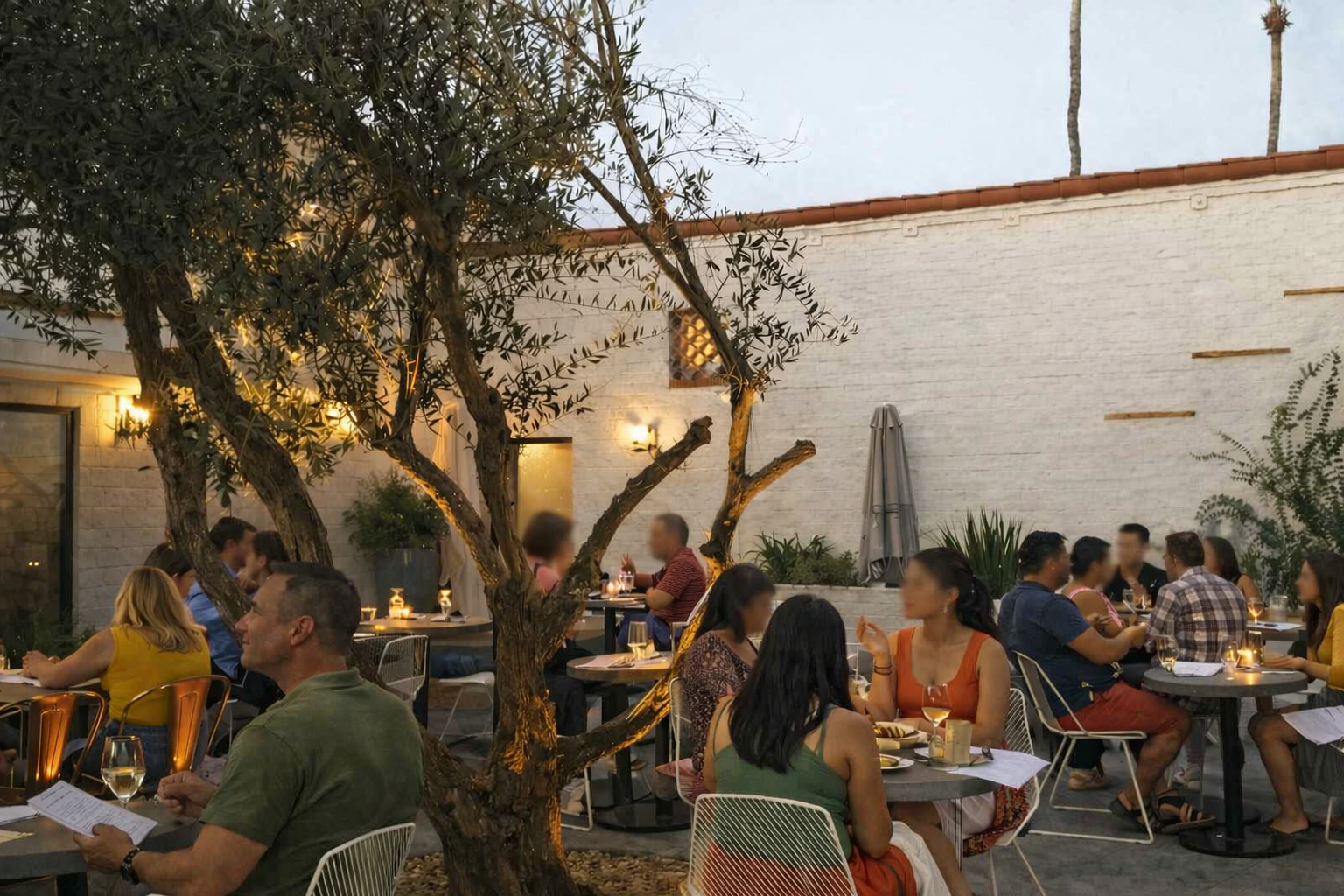 Outdoor patio dining at Workshop Kitchen + Bar with guests seated under evening lighting