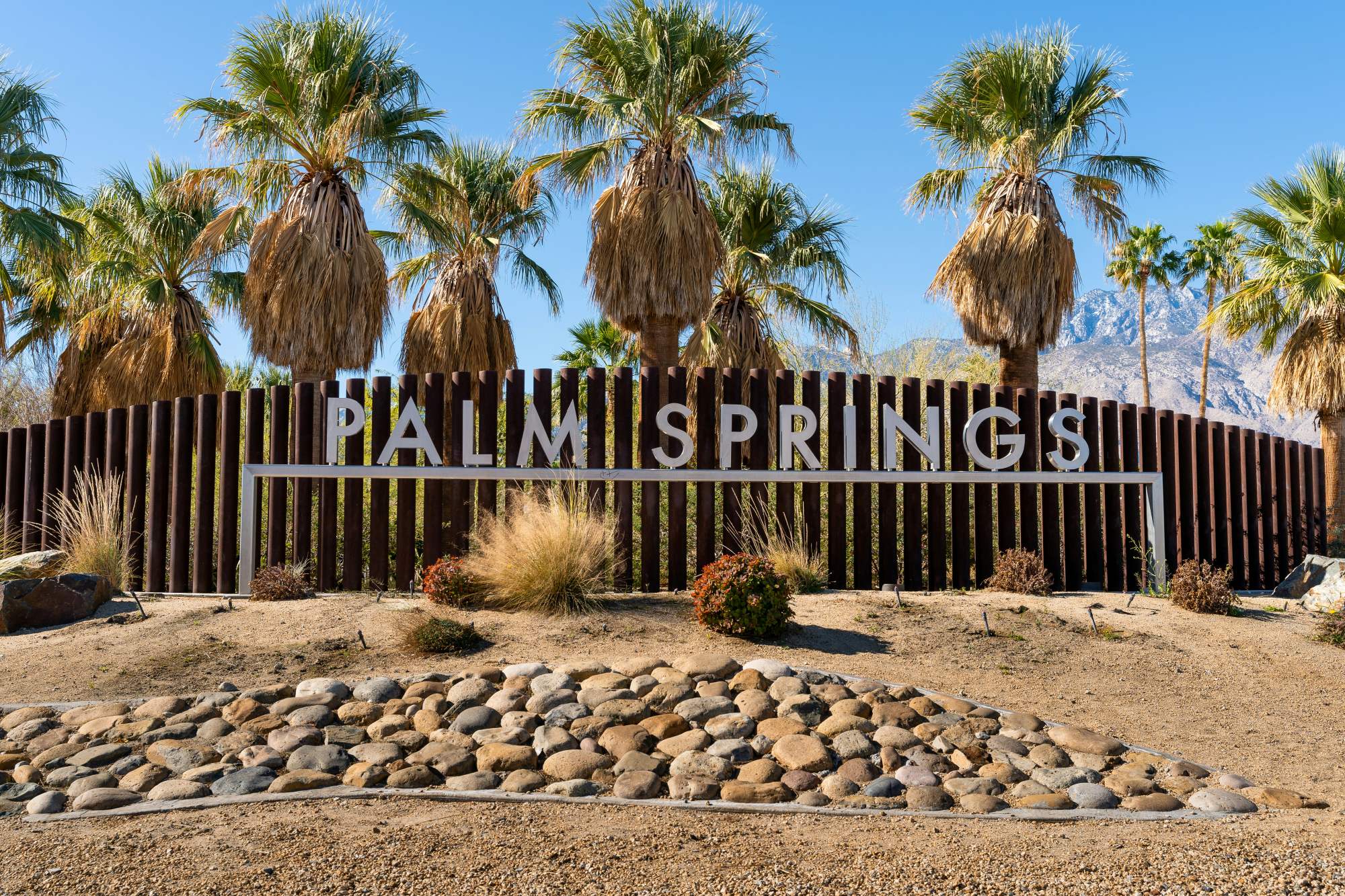 Palm Springs sign with palm trees and mountains in the background
