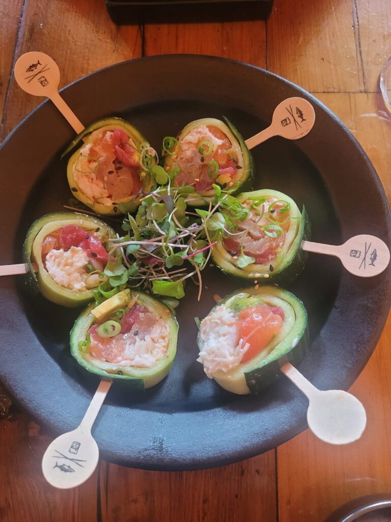 Cucumber‑wrapped sushi lollipops at Sandfish in Palm Springs, served with tuna, salmon, and microgreens.