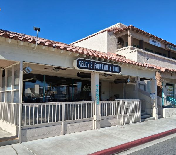 Exterior of Keedy’s Fountain & Grill with stucco facade, red‑tile roof, patio seating, and signage displaying the restaurant name.