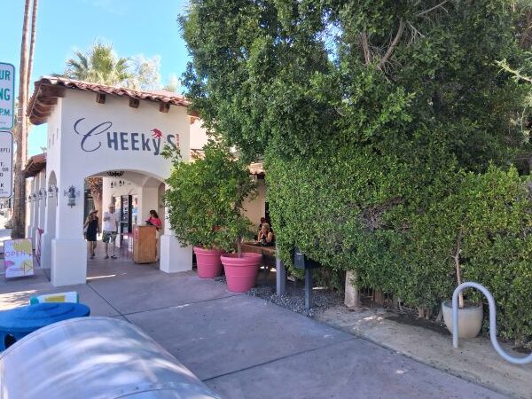 Exterior of Cheeky’s Palm Springs with white stucco walls, pink planters, and a sunny morning backdrop.