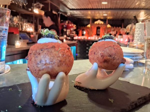 Two caviar‑topped savory donuts served on white ceramic hand sculptures at Counter Reformation.