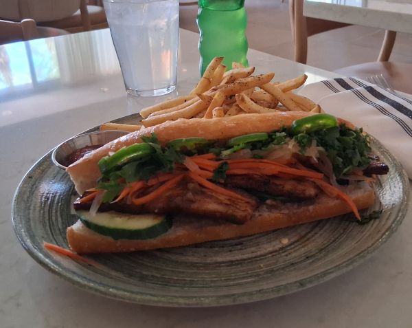 Bánh mì sandwich with pork belly, pickled vegetables, cilantro, jalapeño, and fries.