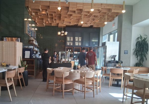 Modern interior of Juniper Table with geometric ceiling, green tile bar, and light wood seating.