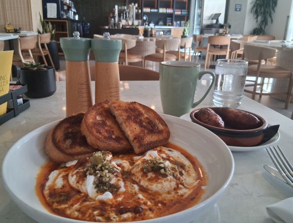 The Turjish Eggs against a backdrop of Juniper Table in Palm Springs. Coffe and chicken apple sausage pictured on the side