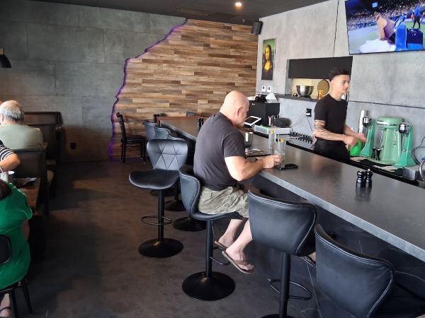 Interior of Project Burger showing the counter, milkshake machines, bar seating, and guests dining inside.