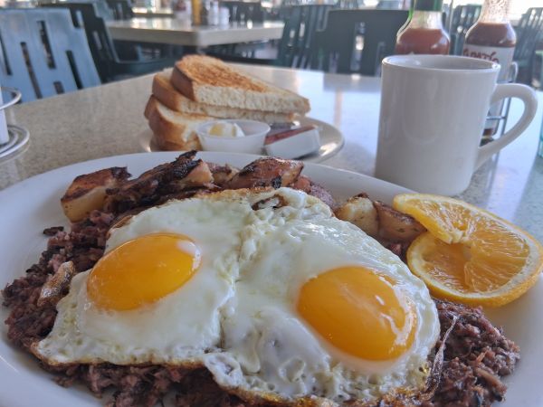 Shermans Corned Beef Hash on the Palm Springs patio, topped with sunny up eggs, housemade sourdough toast and coffee also pictured