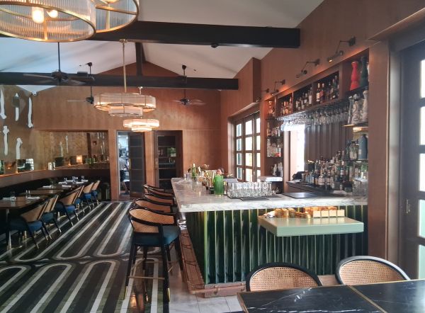 Colony Club’s bar with marble countertop, green paneling, and mid‑century lighting.
