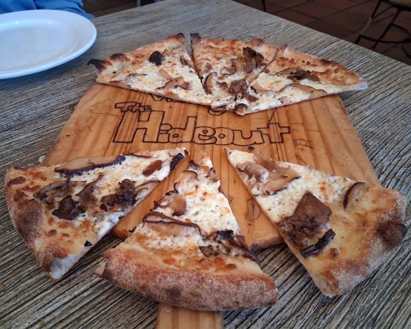 The mushroom pizza, displayed on The Hideout's signature board