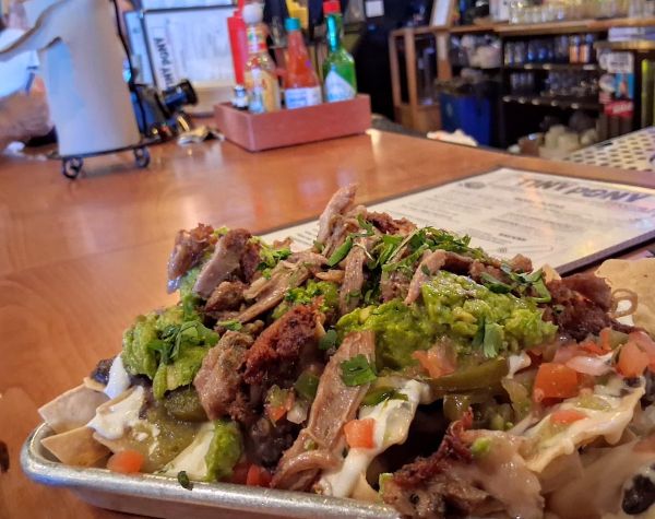 The Duck Confit Nachos at Tiny Pony with logo'd menu behind