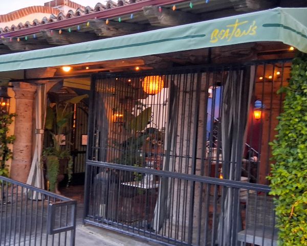 Exterior patio view of Beaton's in Palm Springs beneath the restaurant's signature green awning.