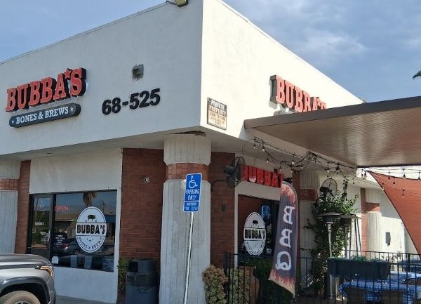 Exterior of Bubba’s Bones and Brews with patio seating, shade sails, string lights, and the restaurant’s red‑and‑black signage.