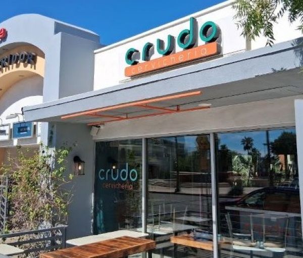 Close‑up of the Crudo Cevichería sign on the restaurant’s modern gray and white facade