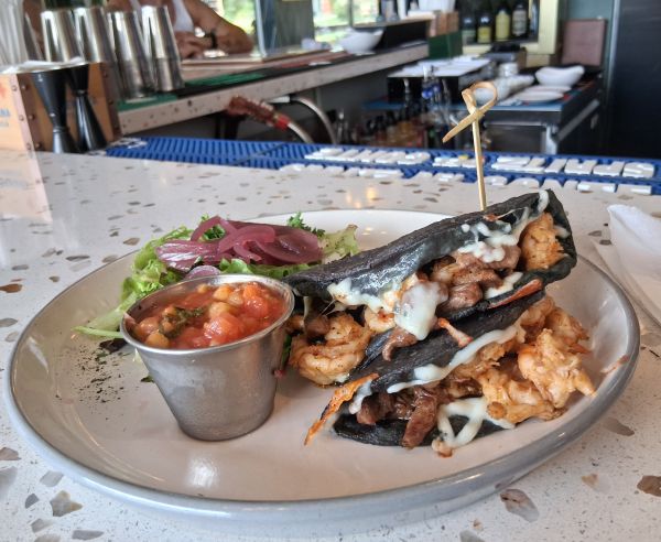 Blue corn tacos filled with steak, shrimp, and melted cheese, served with salsa and a small salad