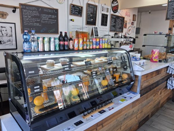 A display case filled with imported French and Italian pastries, labeled and arranged neatly inside the café.