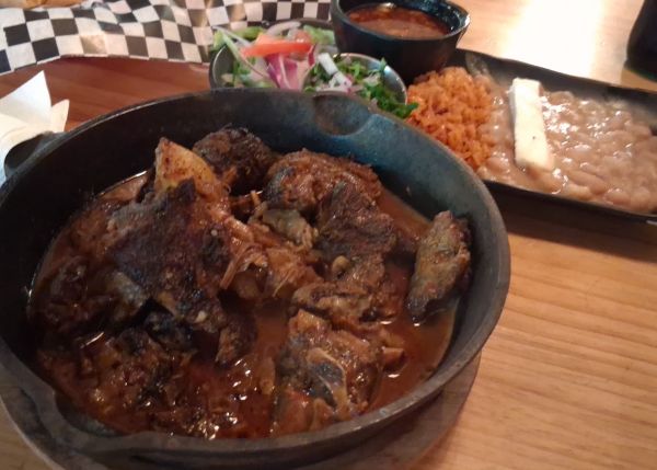 Birria Tatemada in a cast-iron skillet with beans, Spanish red rice, salad and consommé at El Tranvia in Coachella