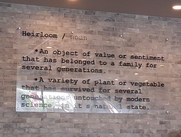 Heirloom definition sign on brick wall at Heirloom Craft Kitchen - an object of value that has belonged to a family for generations