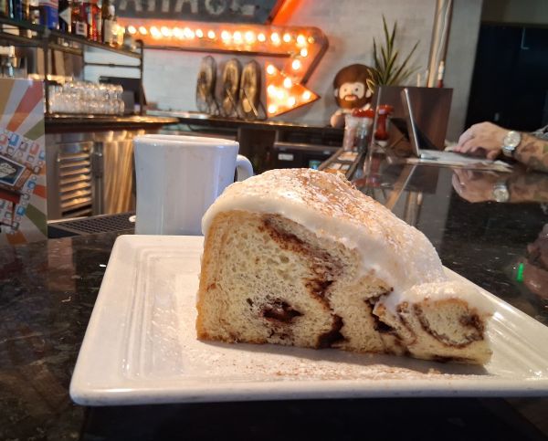 Frosted Cinnamon Roll on a white plate at the bar at Wilma & Frieda in Palm Springs.
