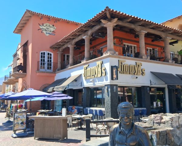 Wilma & Frieda sign on the pink building with balcony seating and a bronze statue in the foreground in Palm Springs.