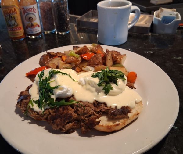 Short Rib Benedict with hollandaise, arugula and home fries on a white plate at Wilma & Frieda in Palm Springs.